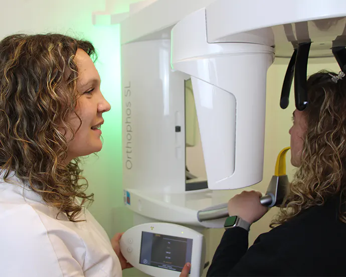 Modernes Röntgengerät im Einsatz mit einer Zahnarzthelferin und einer Patientin